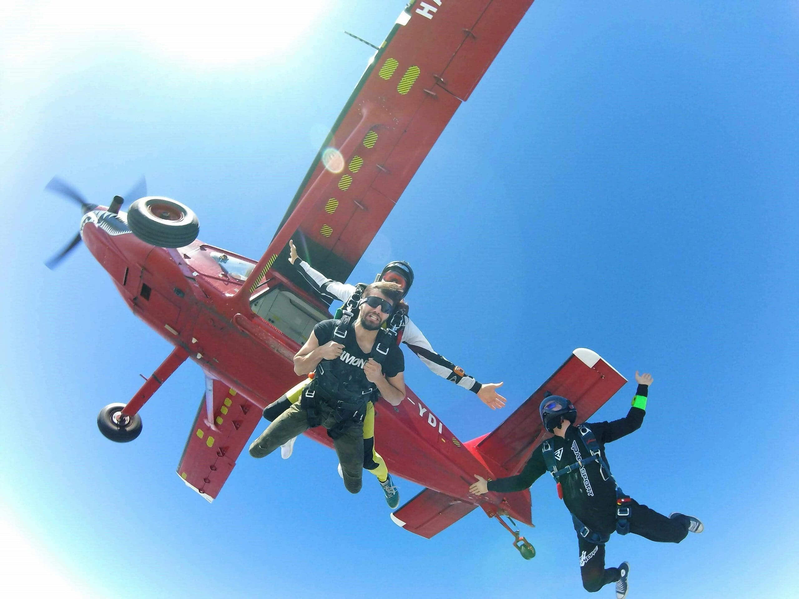 Skydivers jumping from red airplane